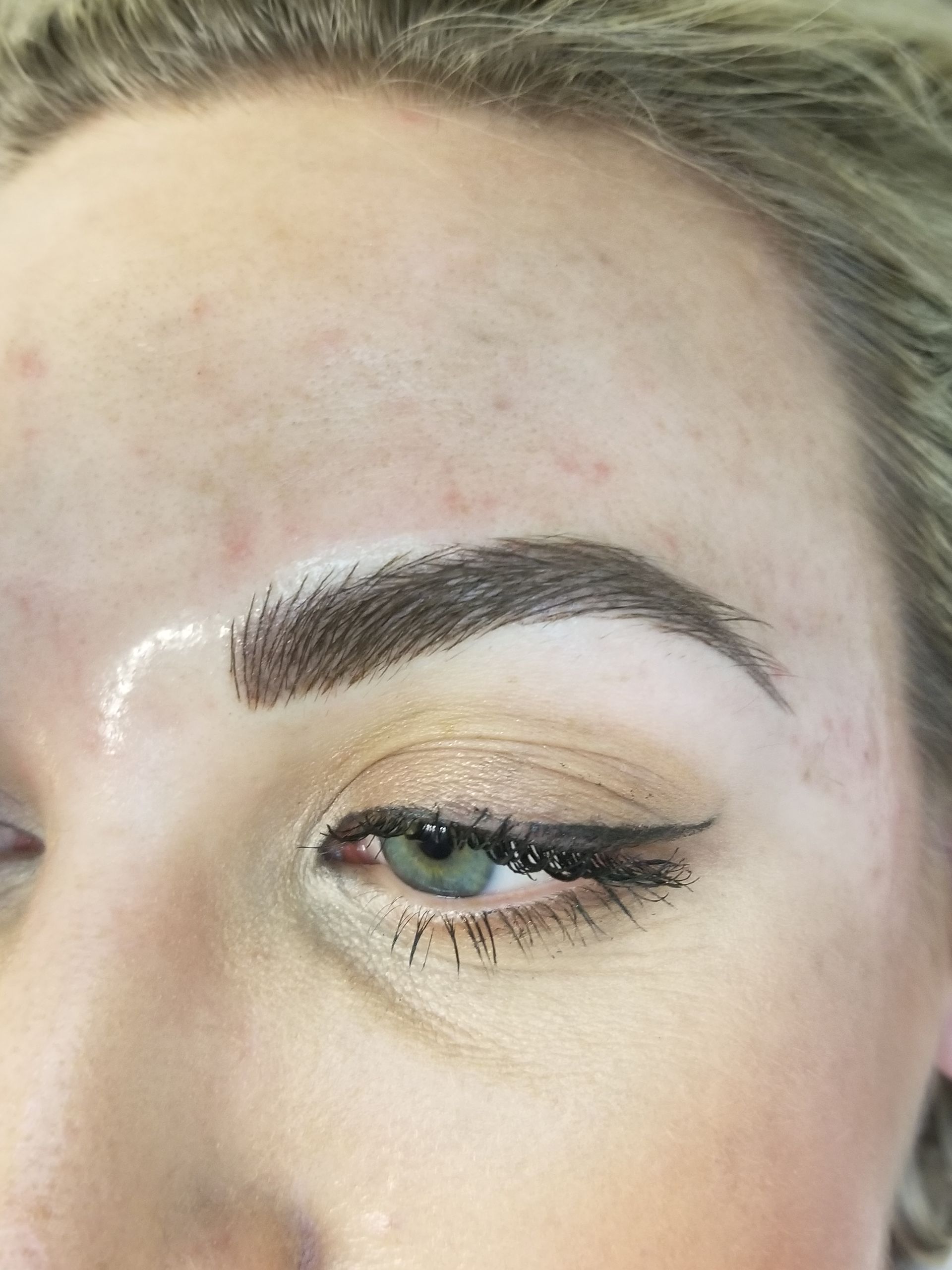 A close up of a woman 's eyebrows with makeup on.