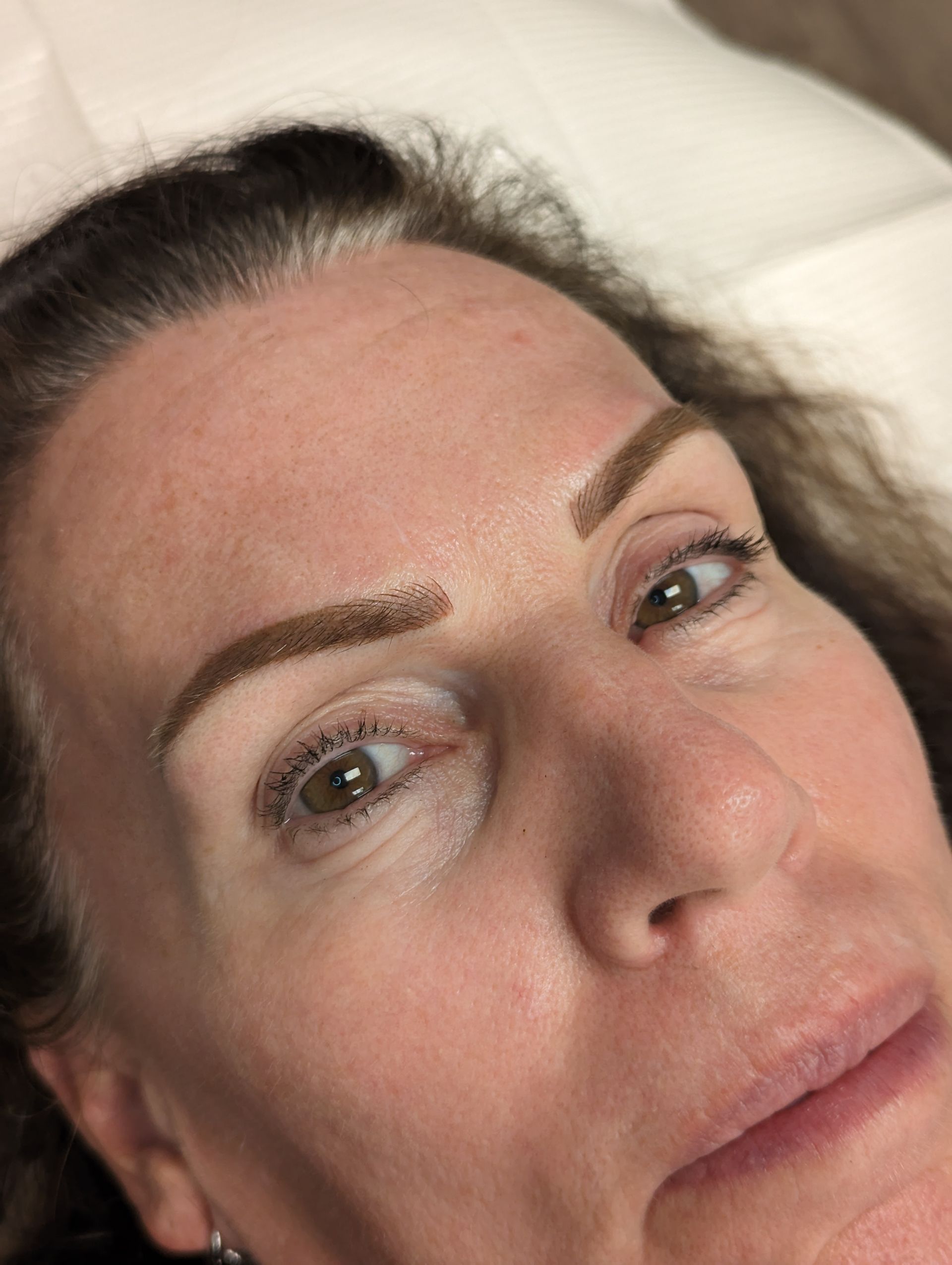 A close up of a woman 's face with a tattoo on her eyebrows.