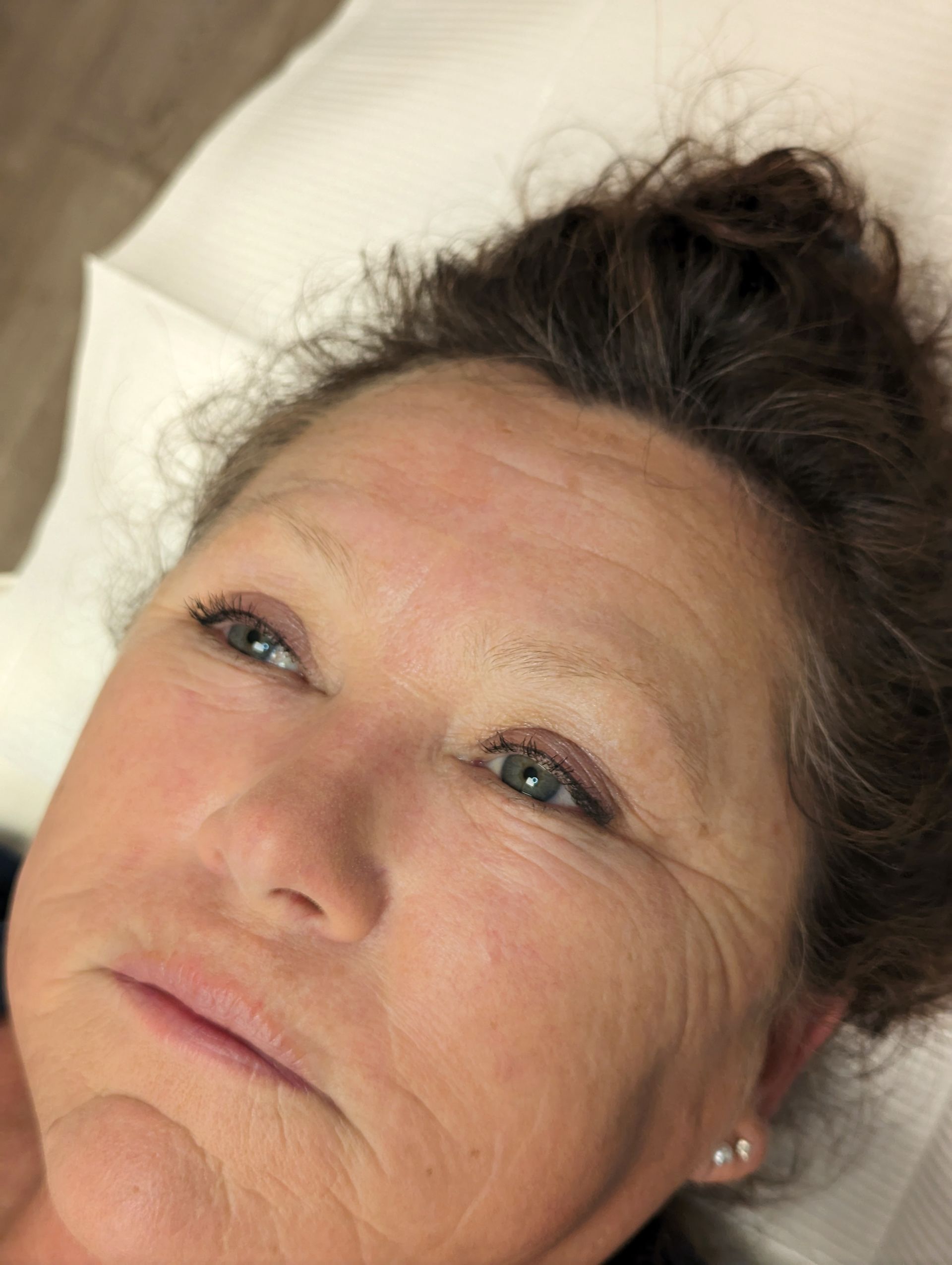 A woman is laying on a bed with her eyes closed and her hair in a bun.