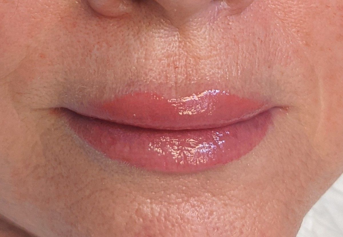 A close up of a woman 's lips with a glossy finish.