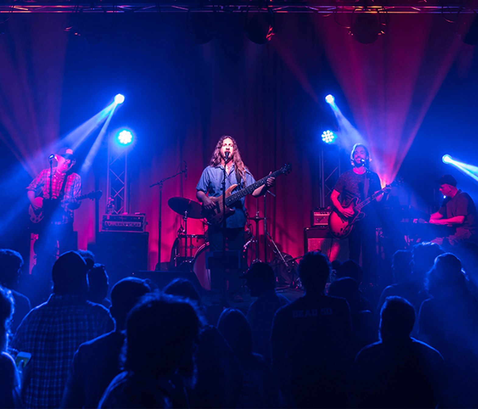A man is singing into a microphone on a stage in front of a crowd.