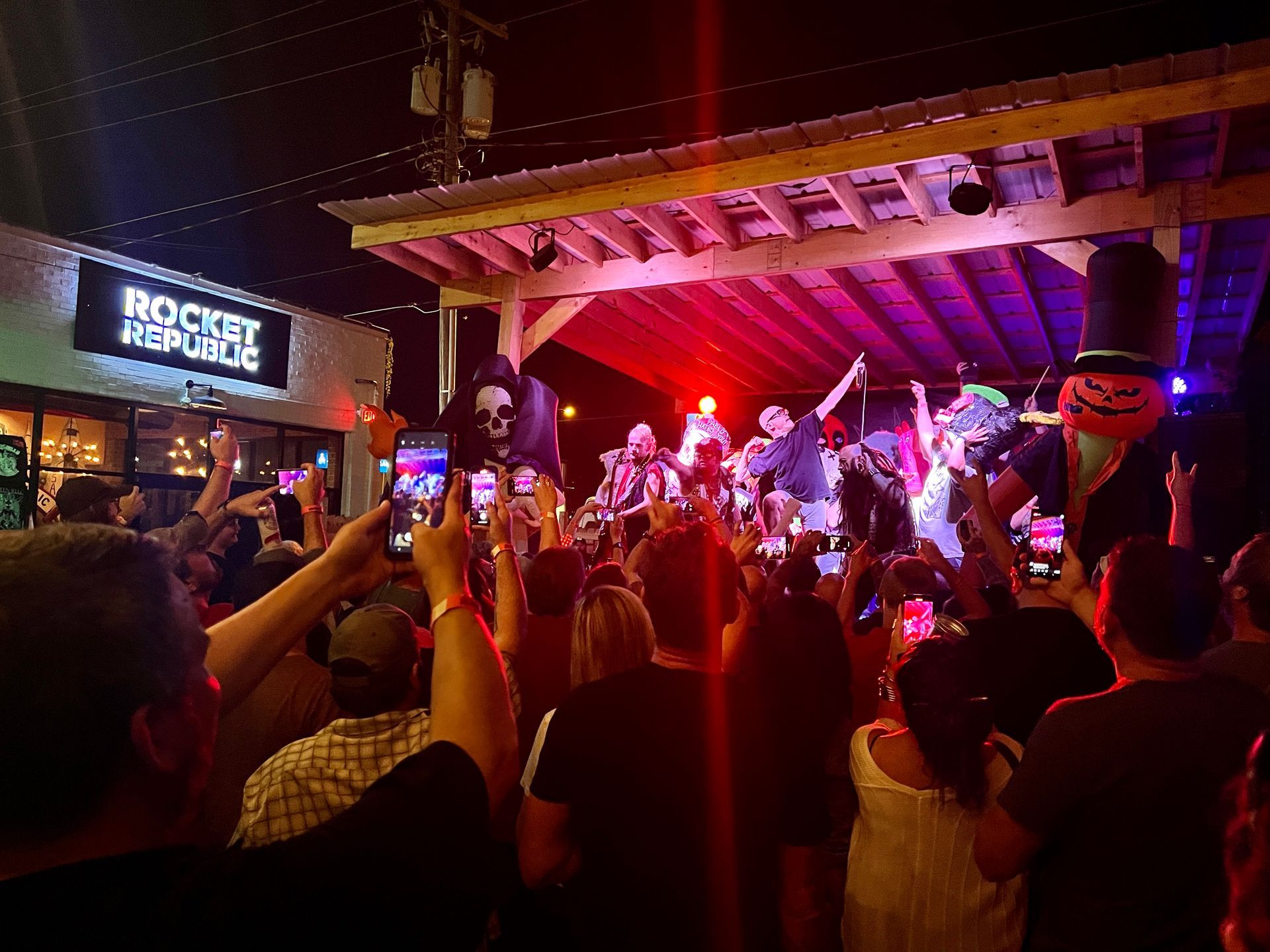 A crowd of people are standing in front of a stage at a concert.