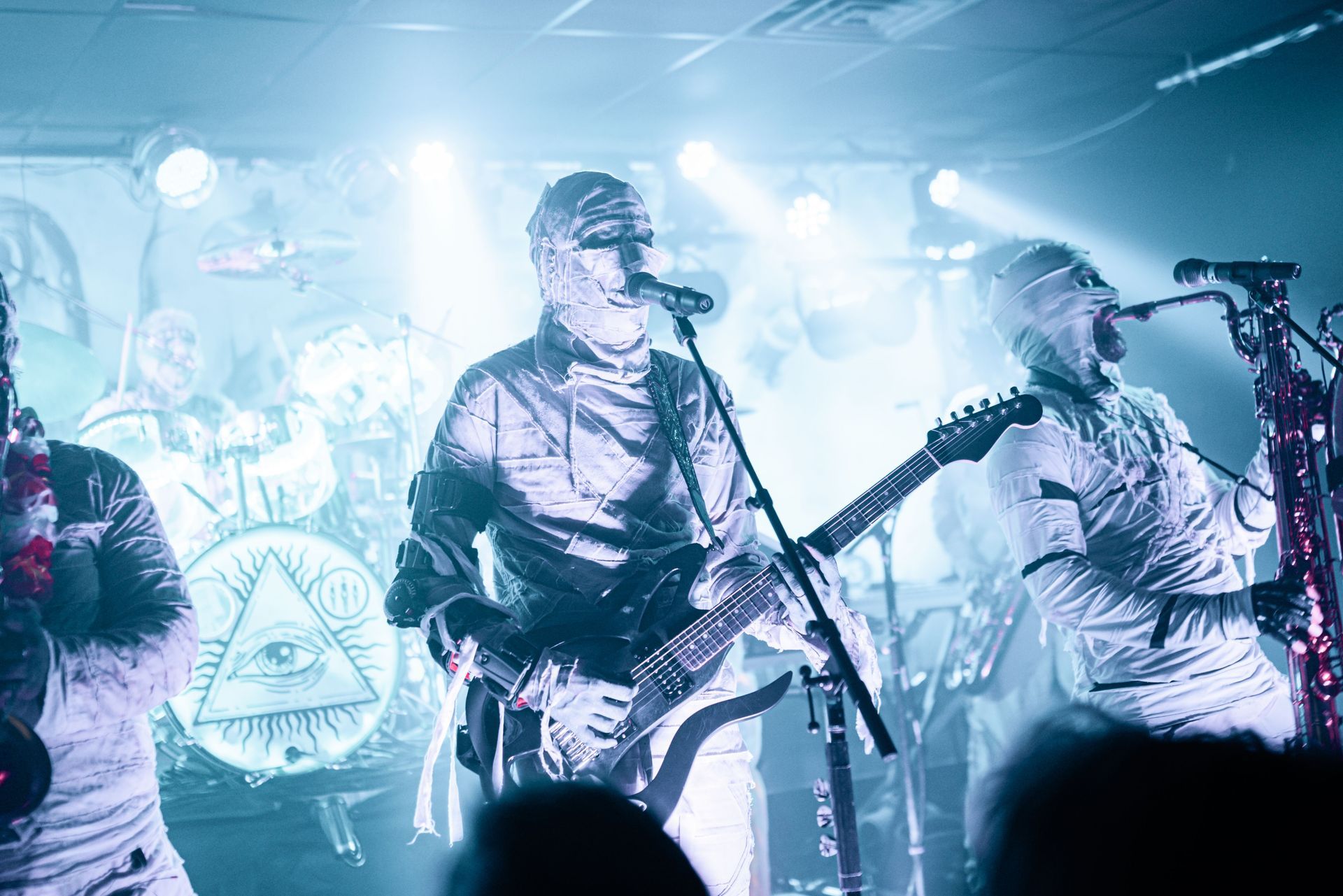 A group of people are playing guitars and singing into microphones on a stage.