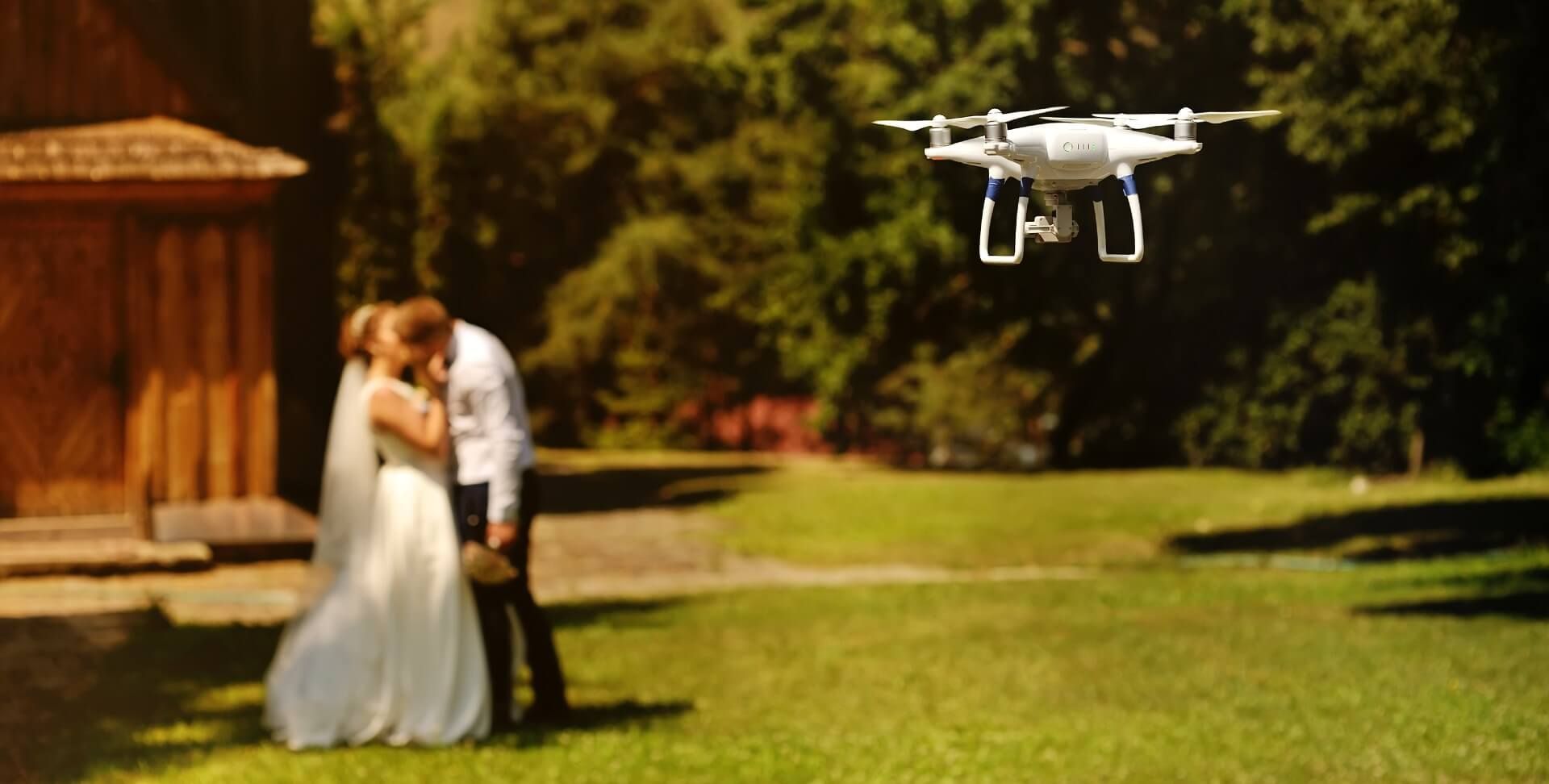 Bride and groom sharing a kiss while a drone films their moment