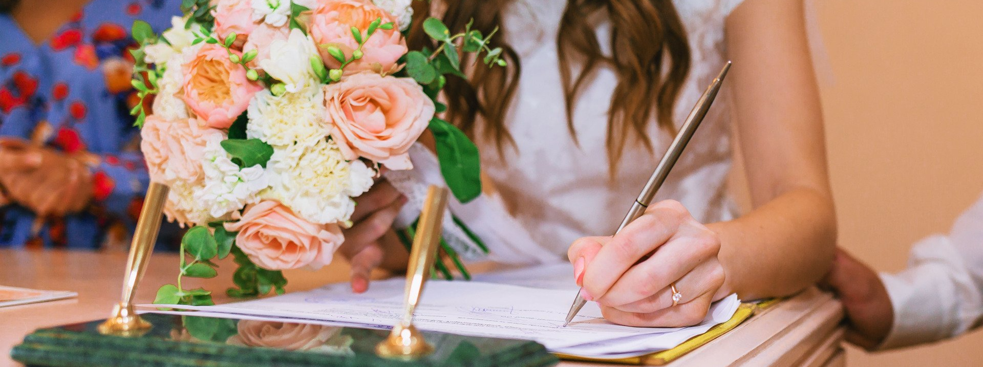 New bride signing her marriage certificate while holding a bouquet