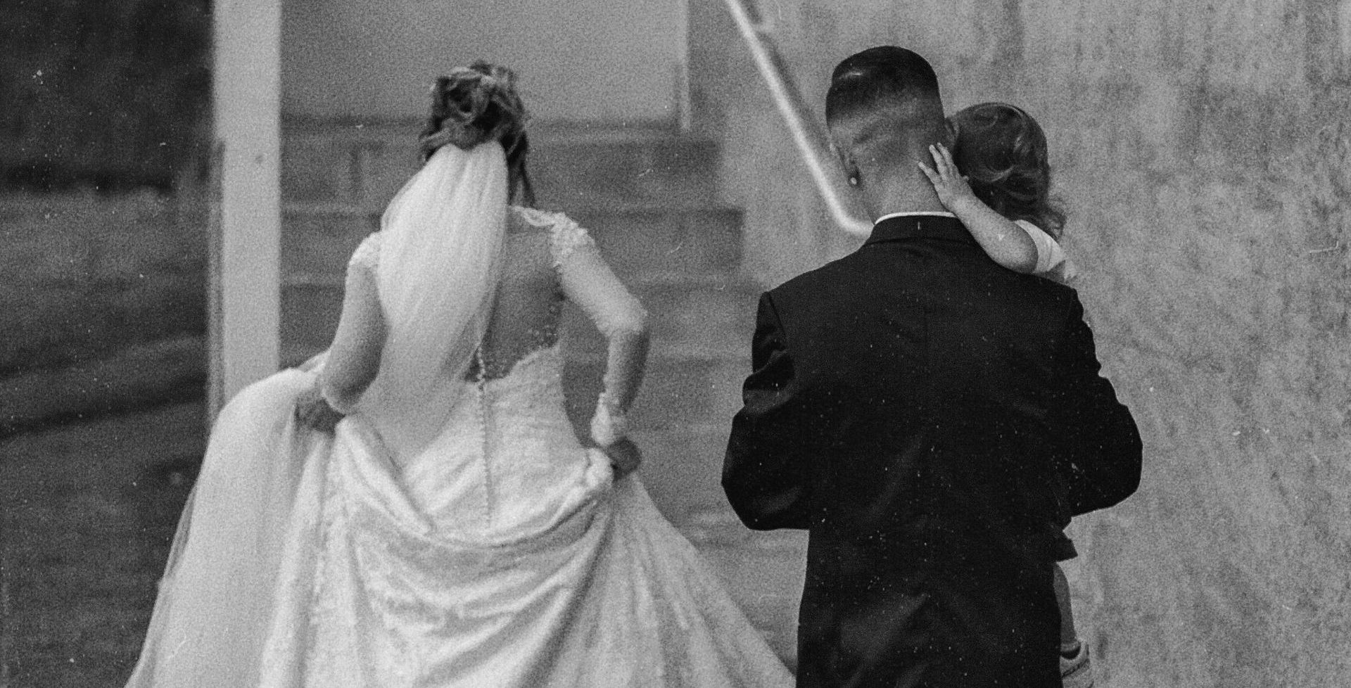 a bride and groom walking to their wedding with their baby