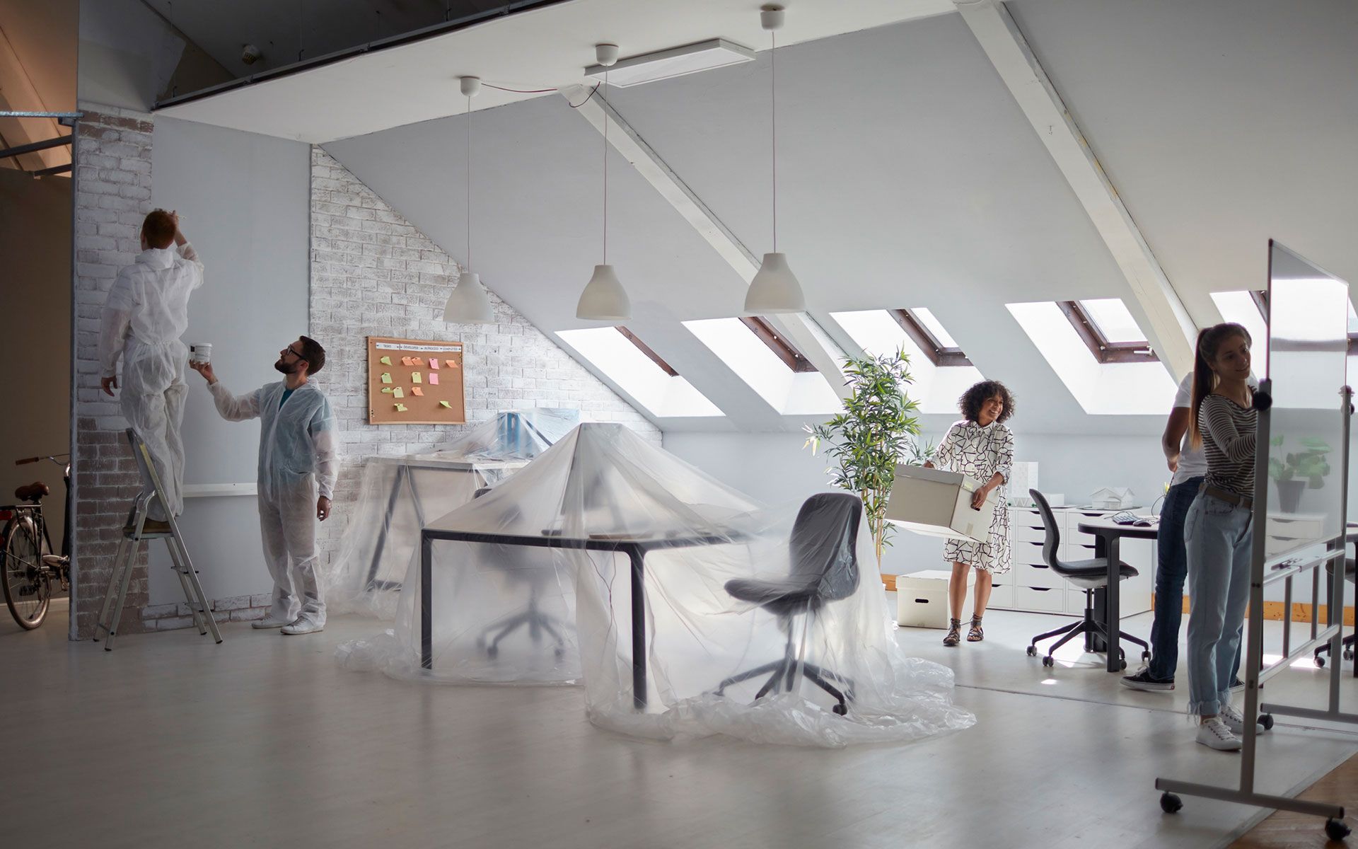 A group of people are painting a room in an office.