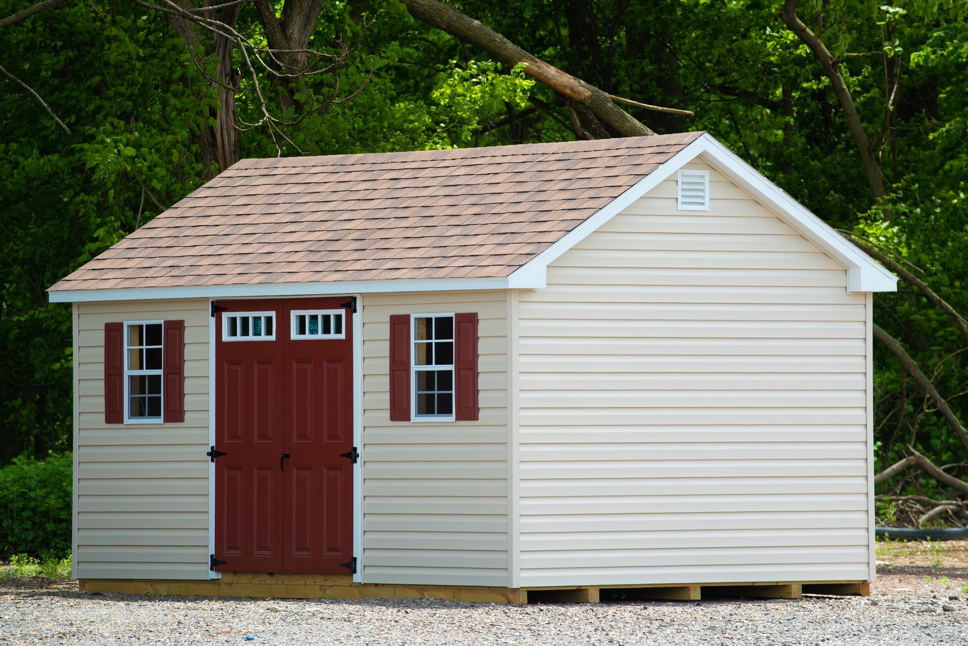 A small white shed with a red door and shutters.