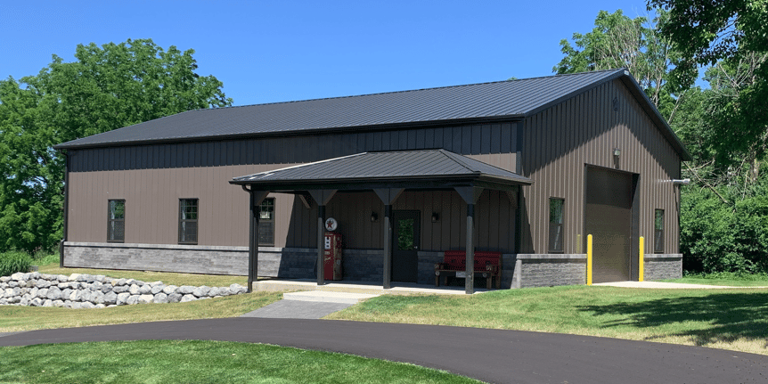A large brown building with a black roof and a porch.
