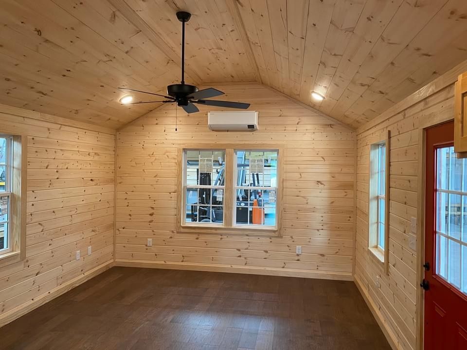 An empty room with wooden walls and a ceiling fan.