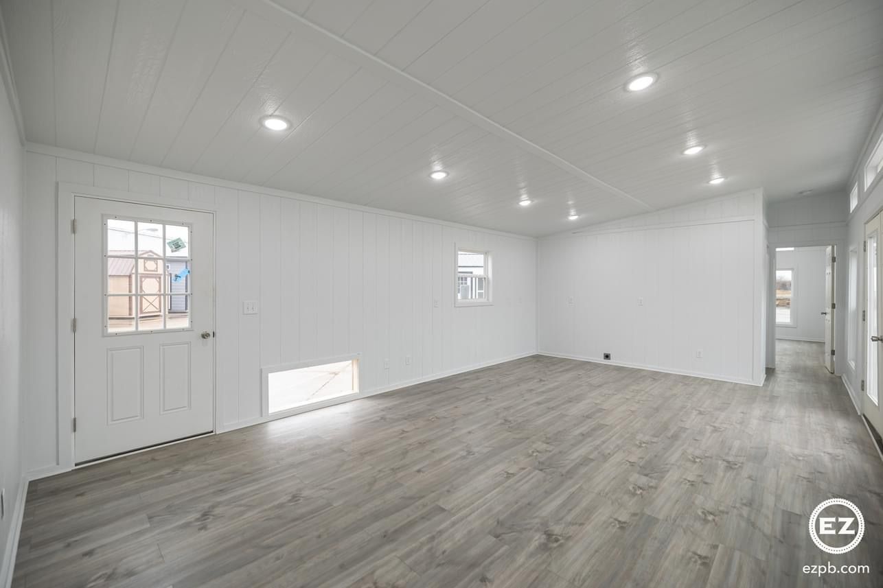 An empty living room with hardwood floors and white walls.
