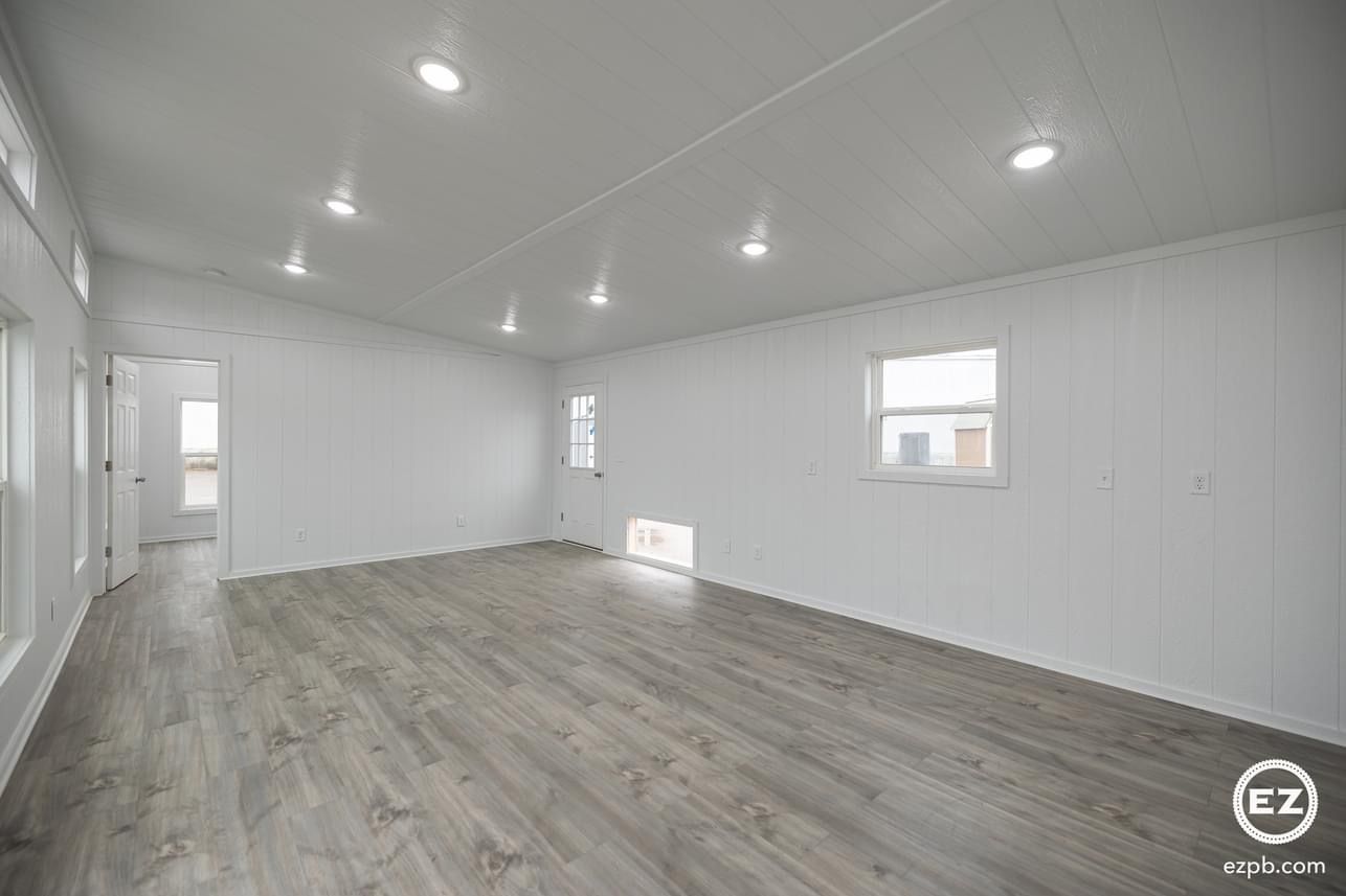 A large empty room with hardwood floors and white walls.