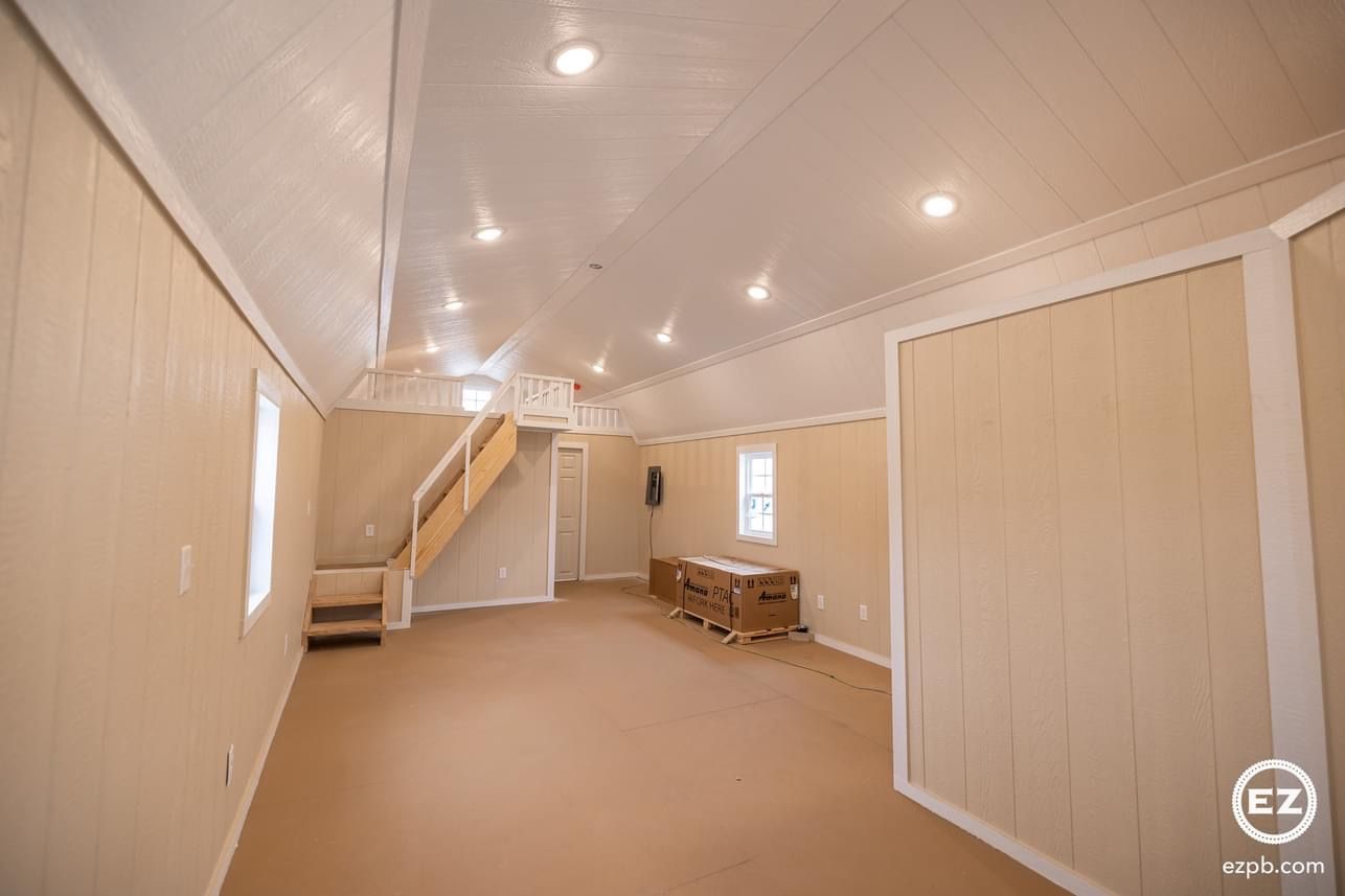 A large empty room with a staircase leading up to the second floor.