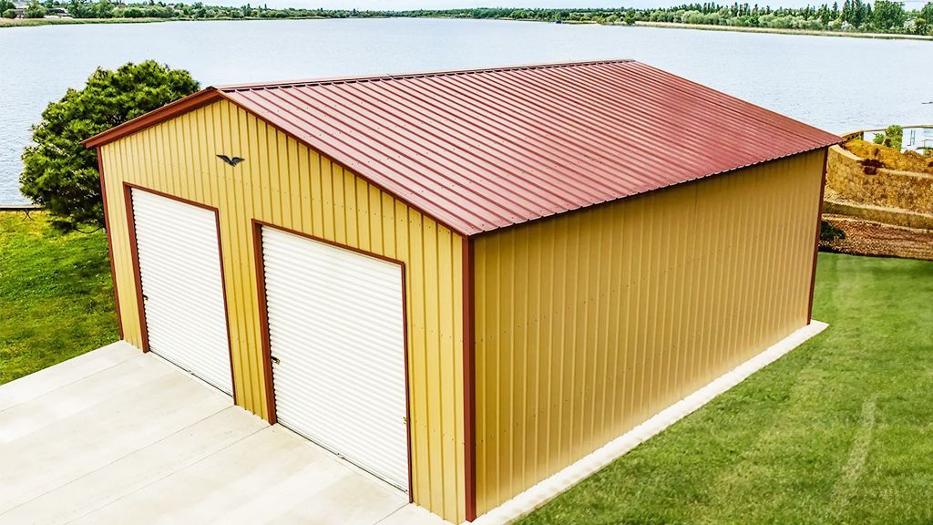 A metal garage with a red roof is sitting next to a lake.