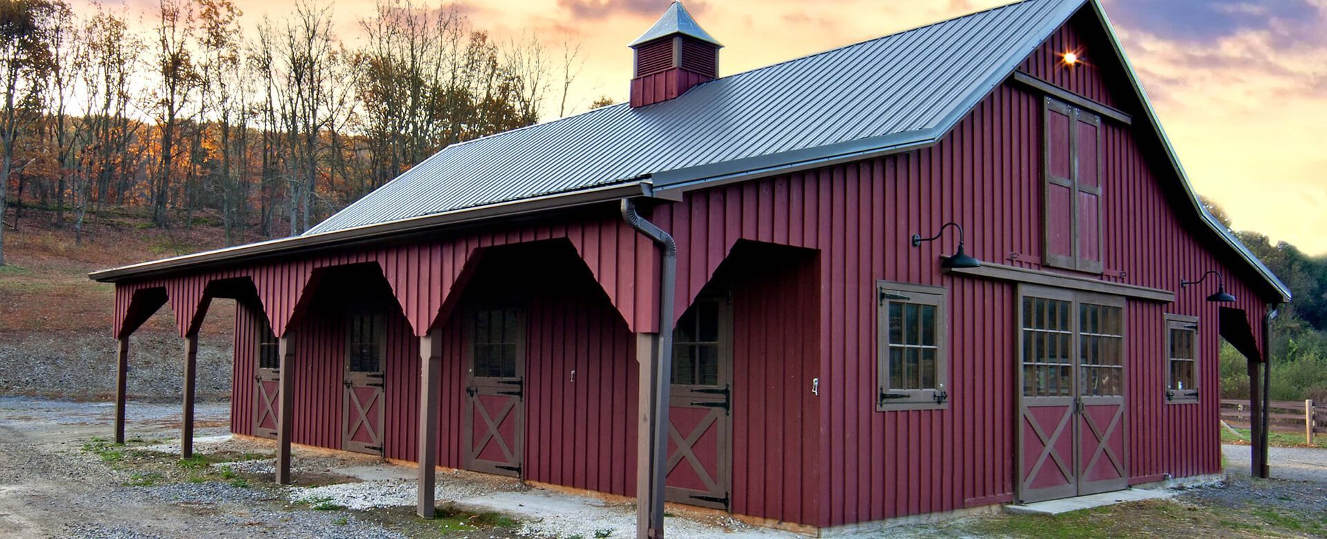 A large red barn with a metal roof and a porch.