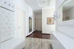 Bright white hallway with white doors, accents, and dark wood floor.