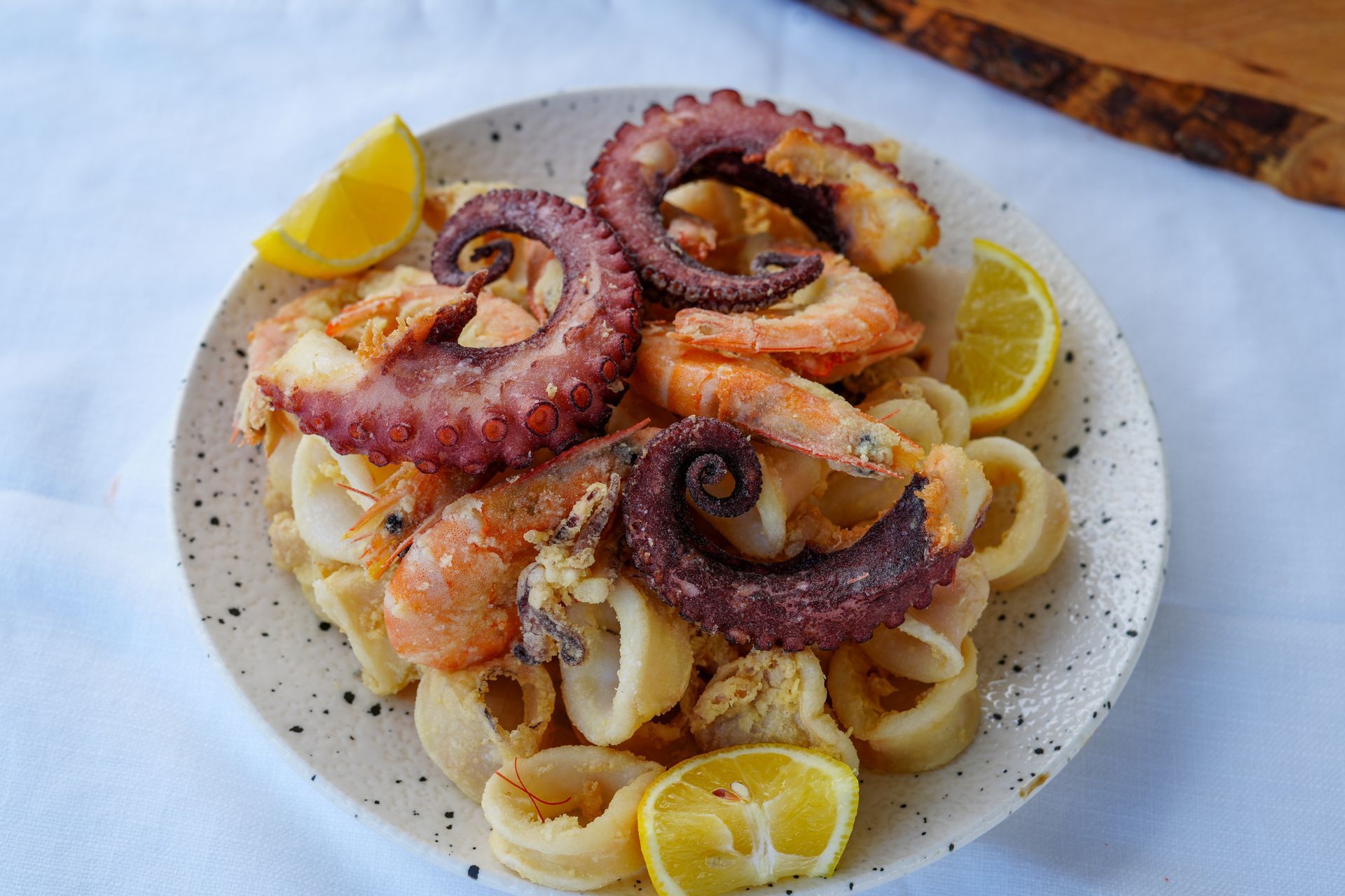 Piatto di frutti di mare fritti con spicchi di limone. Polpo, gamberi e calamari.