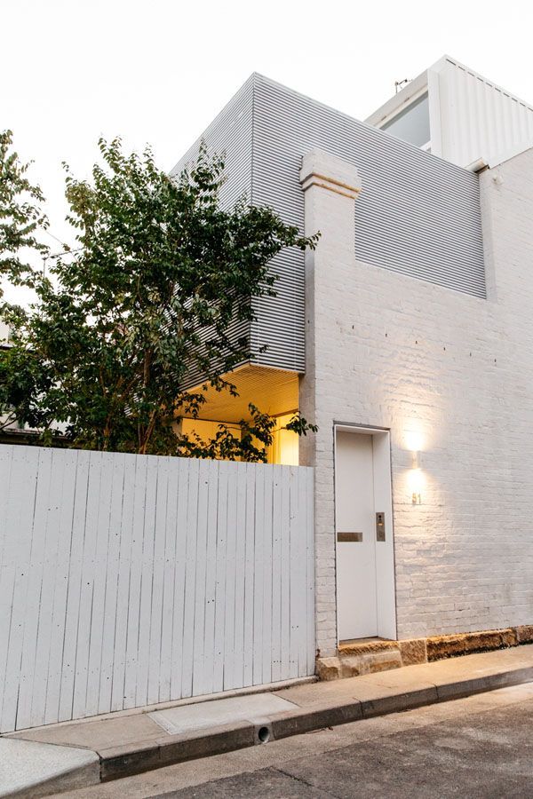 Modern white house facade with a front gate, small tree, and warm wall light by the street — Fineworx Joinery in Warnervale, NSW