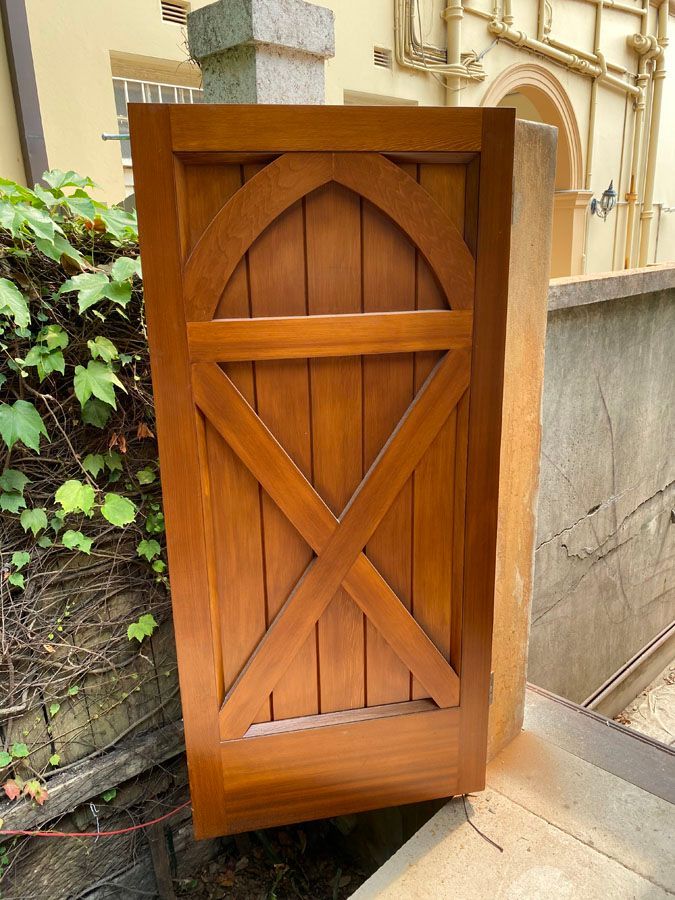 Wooden cabinet door leaning outdoors beside a stone wall and plants — Fineworx Joinery in Warnervale, NSW