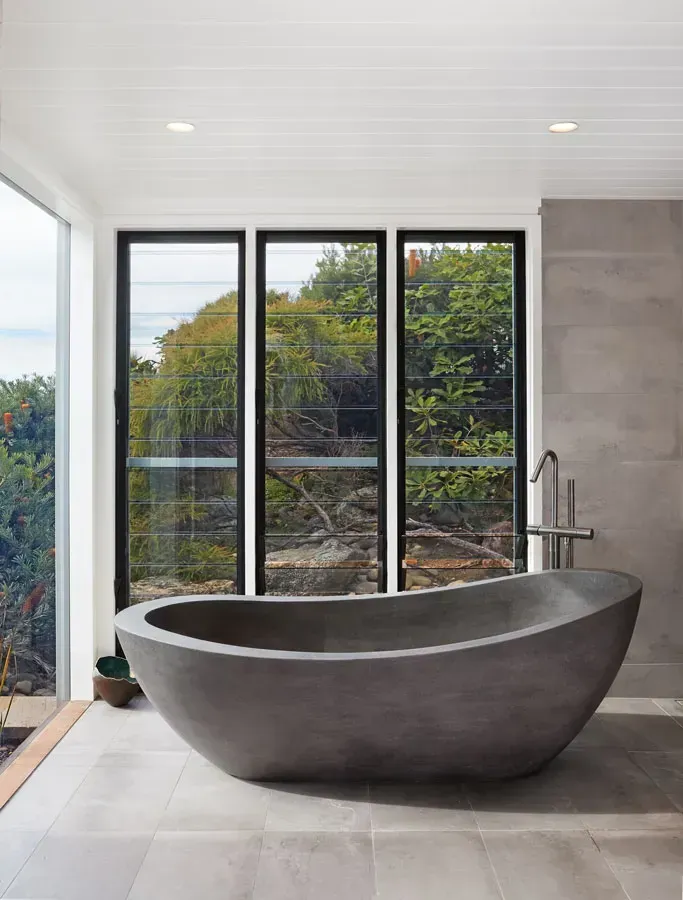 Modern bathroom with a freestanding dark grey oval tub beside large windows and a walk-in shower — Fineworx Joinery in Central Coast, NSW