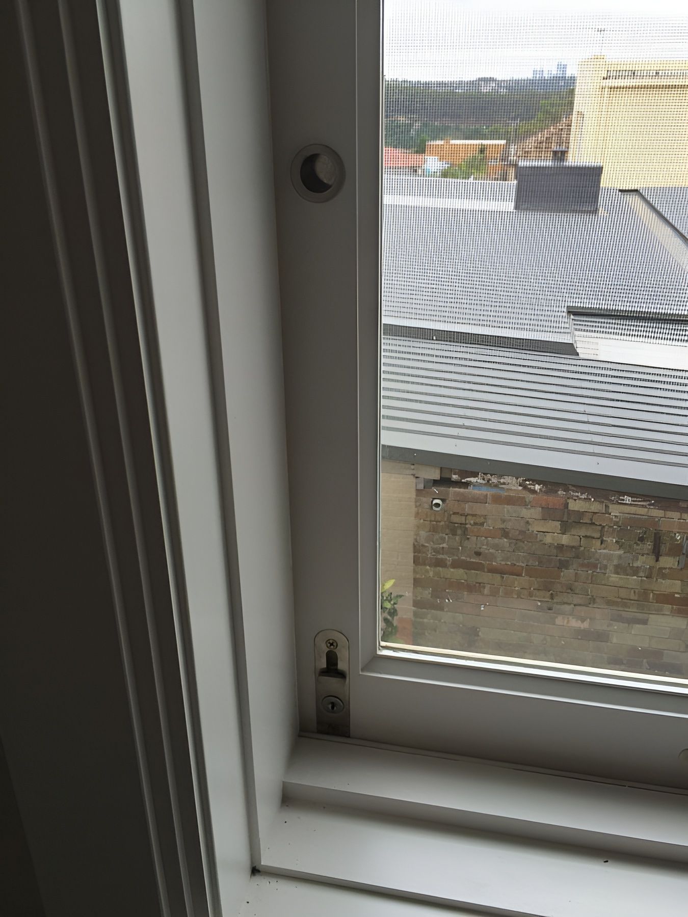Window with Mesh Screen Overlooking Rooftops and A Brick Wall — Fineworx Joinery in Warnervale, NSW