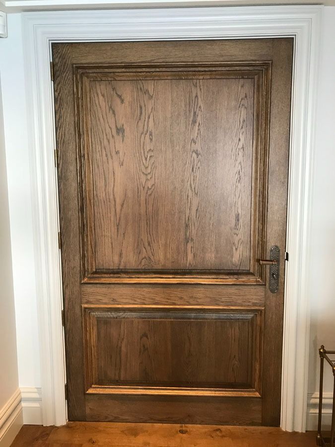 Closed Wooden Door with White Trim and Decorative Paneling in A Hallway — Fineworx Joinery in Warnervale, NSW