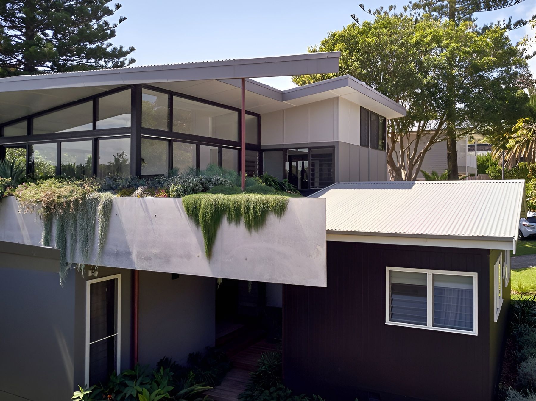 Modern House Exterior with Glass Balcony and Dark Lower Facade Surrounded by Trees — Fineworx Joinery in Warnervale, NSW