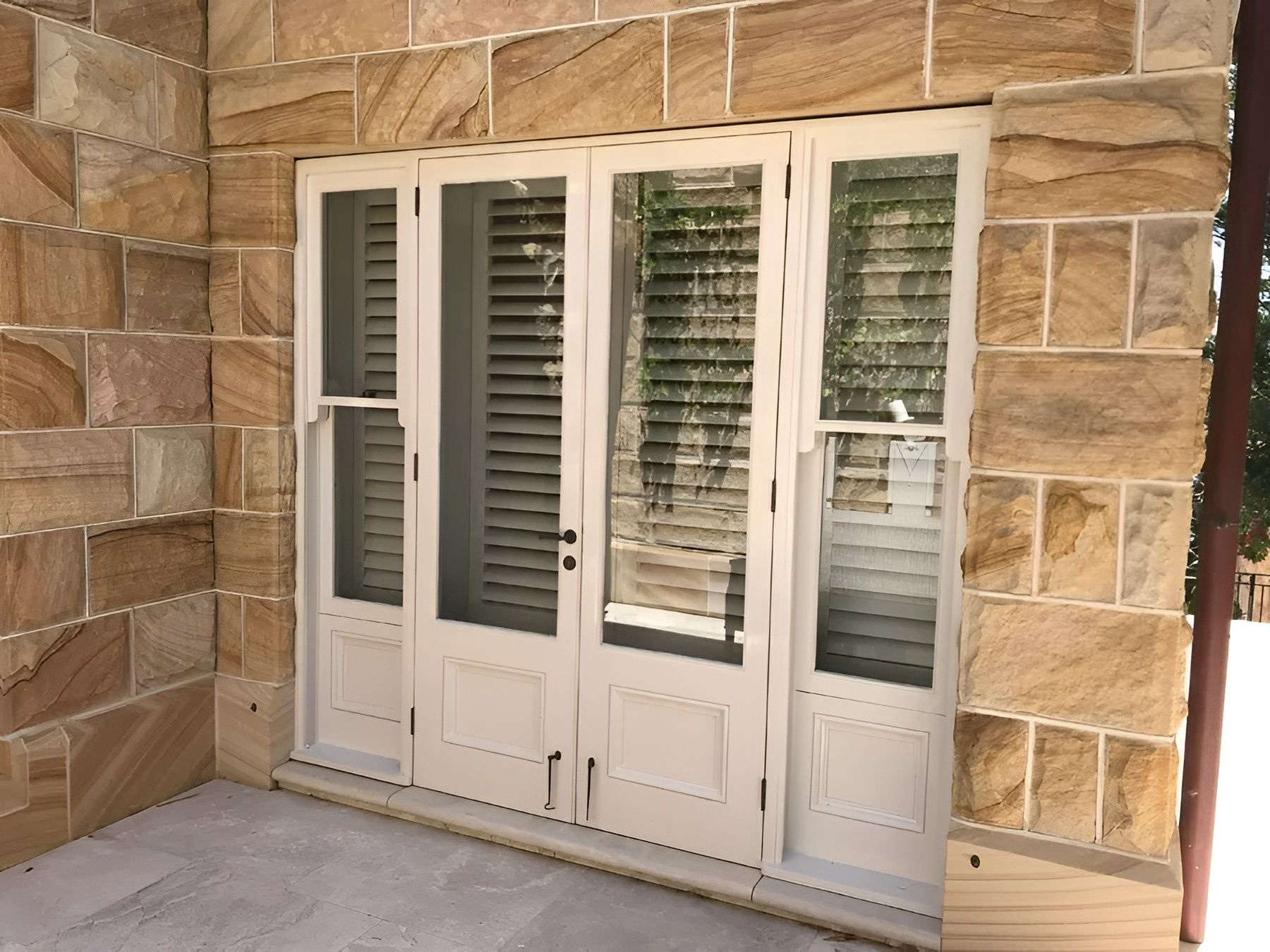 White French Doors with Shutters Set in A Tan Stone Wall on A Porch — Fineworx Joinery in Warnervale, NSW