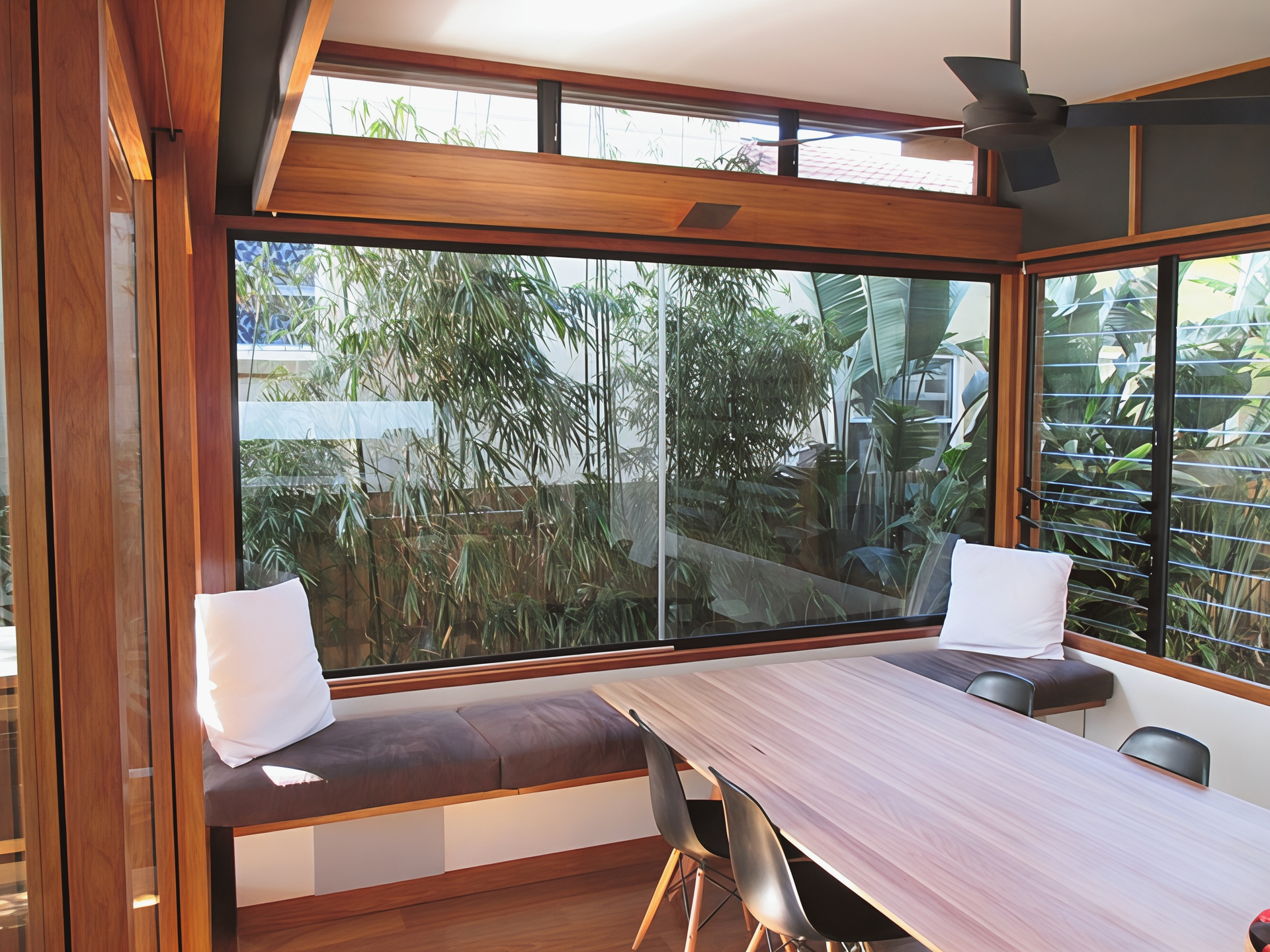 Wood-panelled patio dining area with built-in bench seating and large window overlooking greenery — Fineworx Joinery in Warnervale, NSW