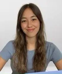 Woman with long, wavy brown hair, wearing a blue shirt, smiling at the camera.