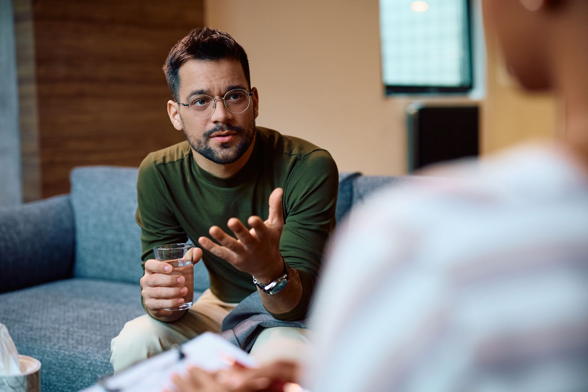 Therapist taking notes during a session with a patient on a couch.