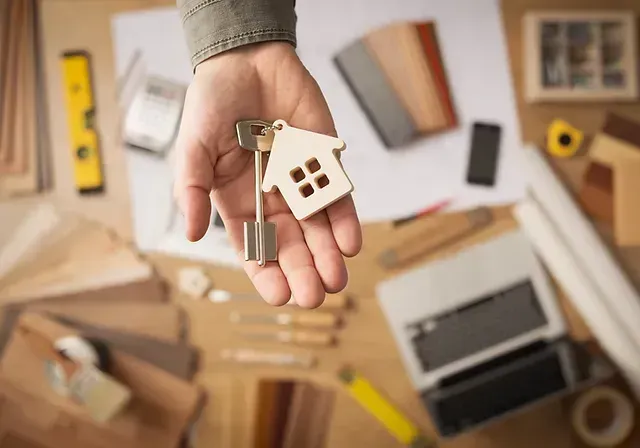 A hand with a skeleton key and a house-shaped key ring.