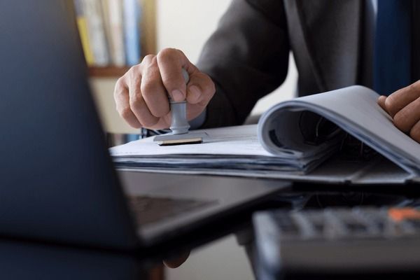 A person's hand stamping some papers.