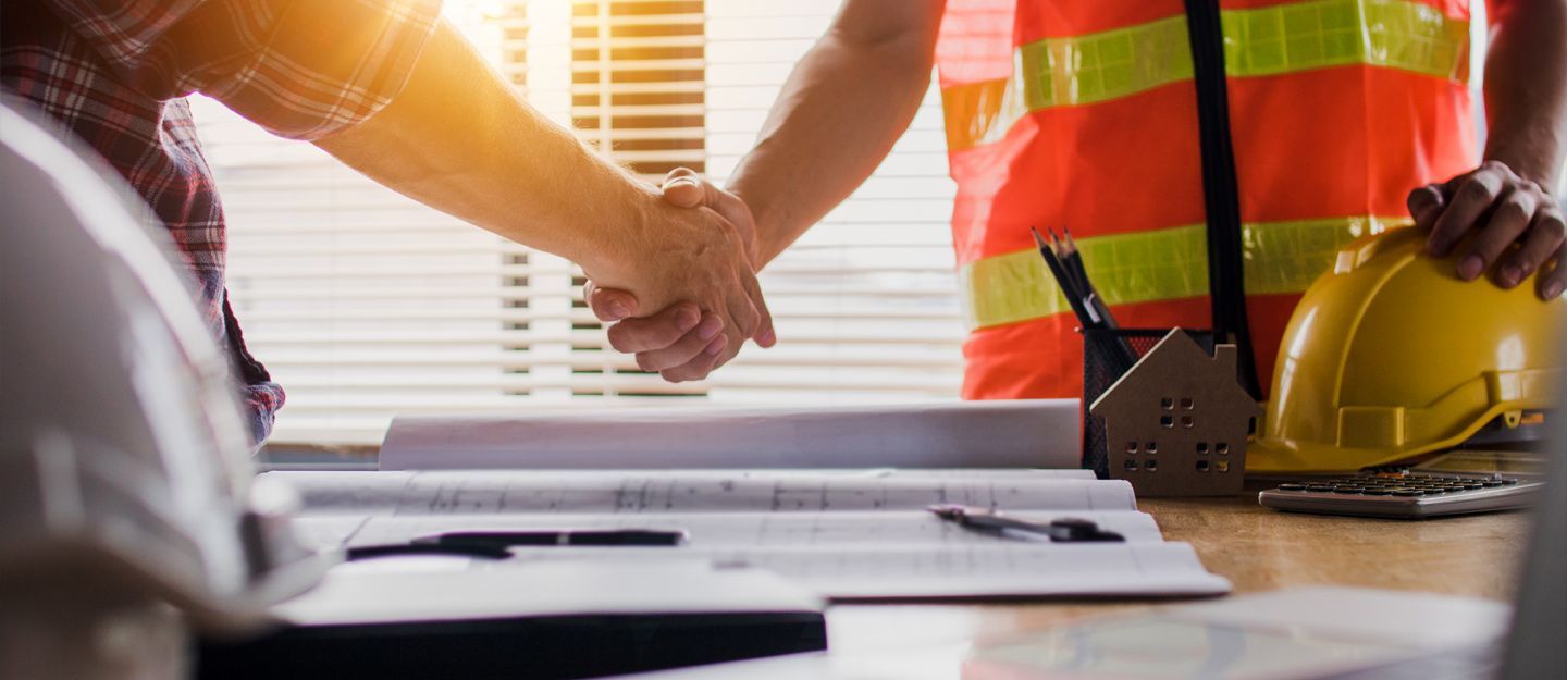 Two construction workers are looking at a blueprint at a construction site.