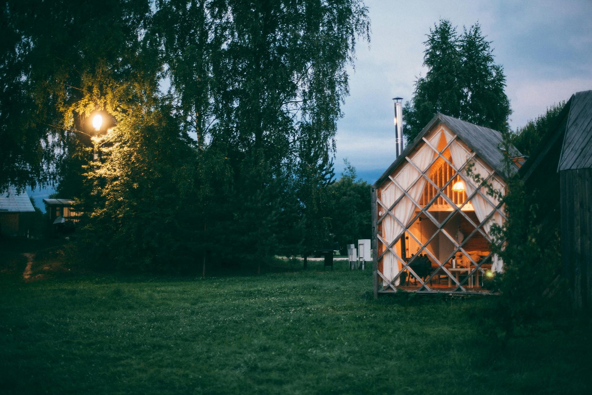 A small house is sitting in the middle of a lush green field.