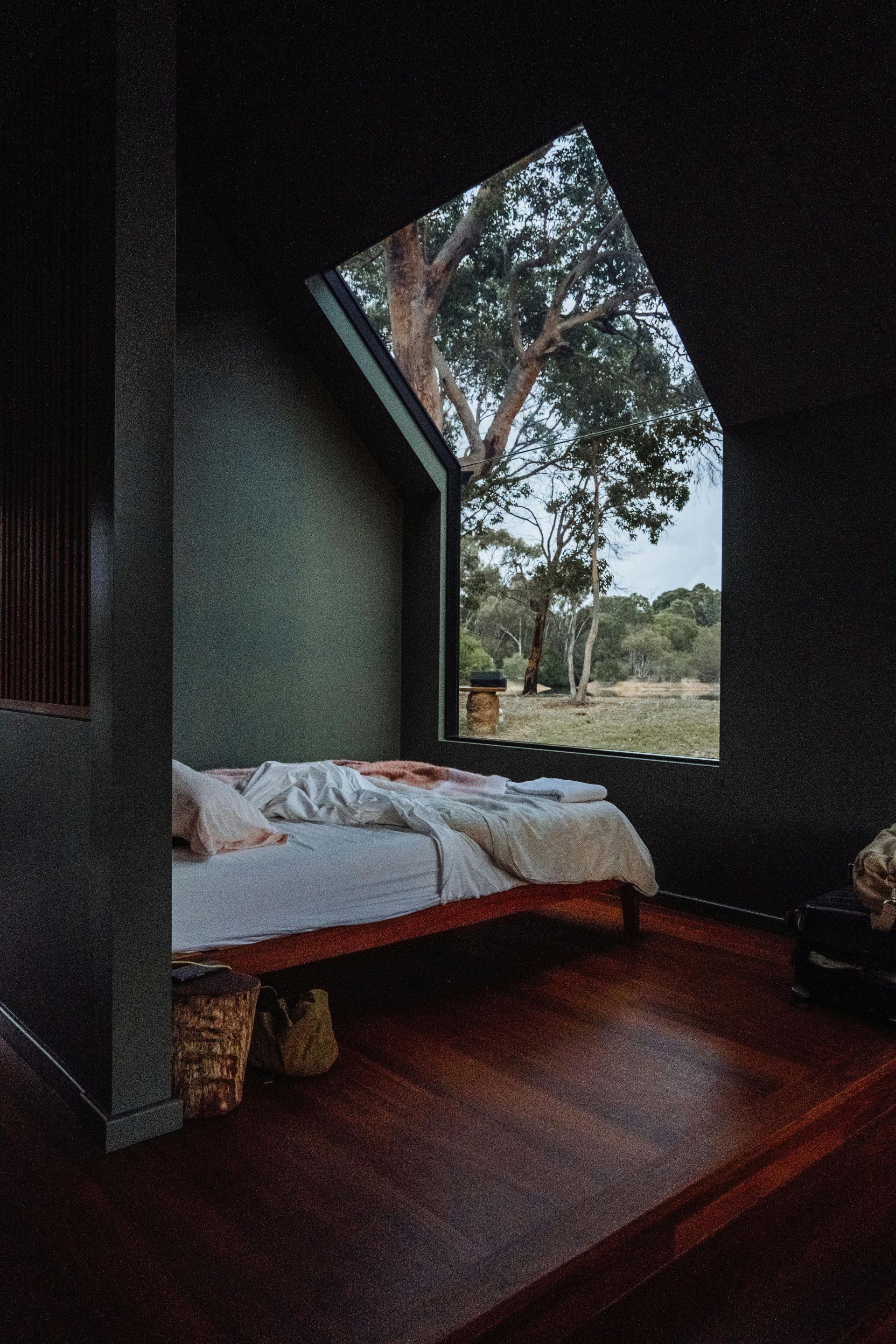 A dark bedroom with an unmade bed