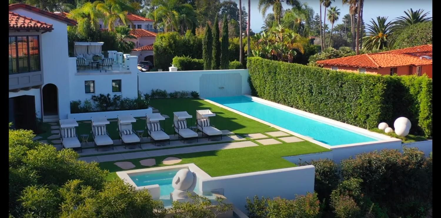 An aerial view of a house with a large swimming pool in the backyard.