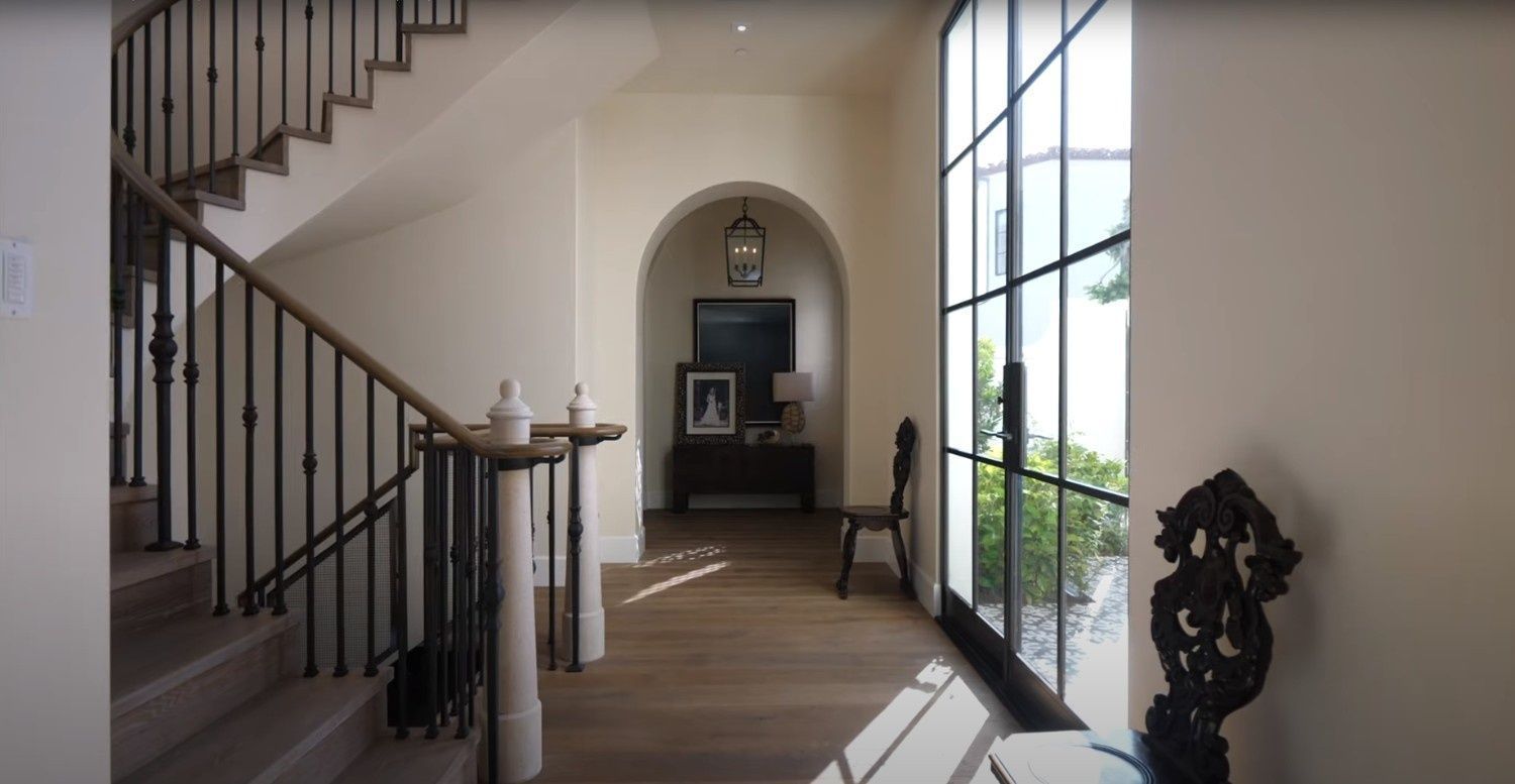 A hallway with stairs and a large window in a house.