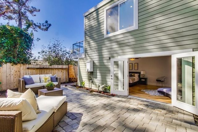 There is a patio with a couch and chairs in front of a house.
