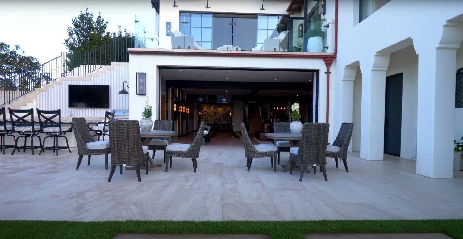 A patio with tables and chairs in front of a large house.