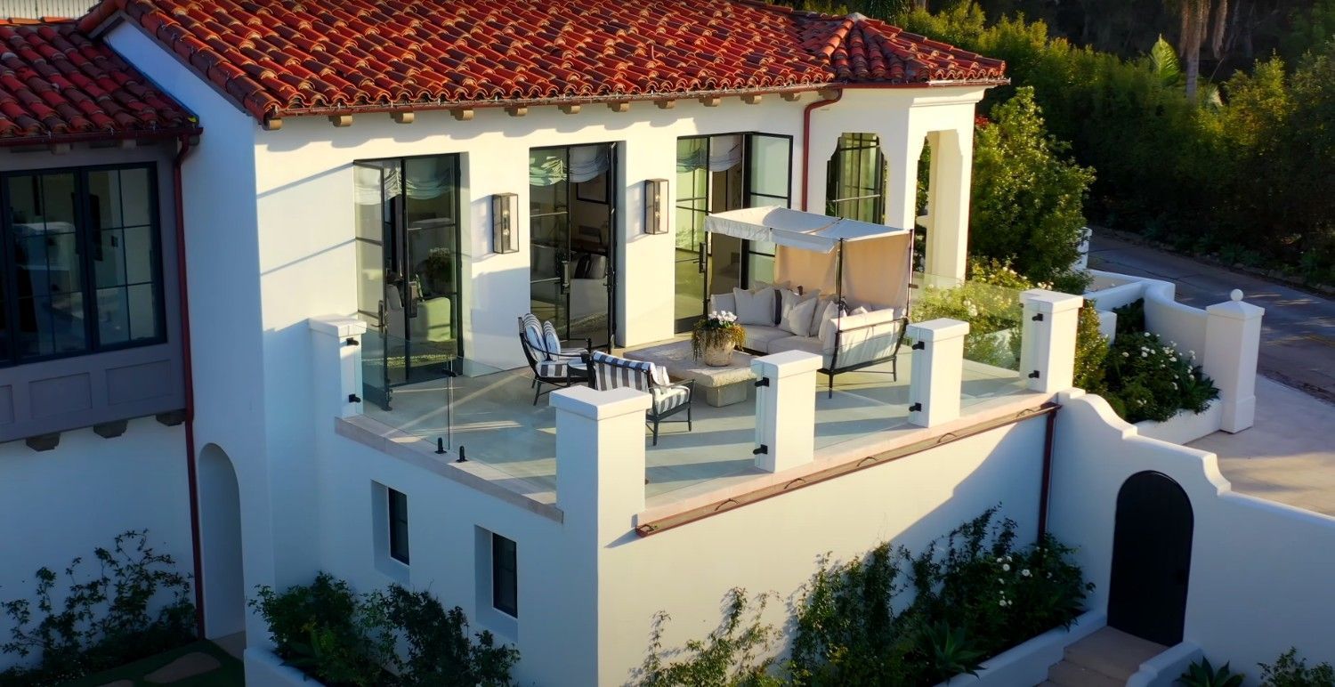 An aerial view of a white house with a red tile roof.