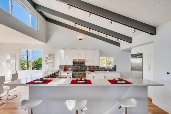 A kitchen with a vaulted ceiling and white cabinets