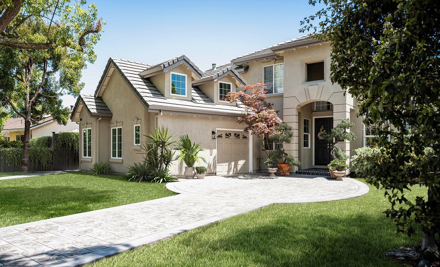 A large house with a driveway leading to it is surrounded by trees and grass.