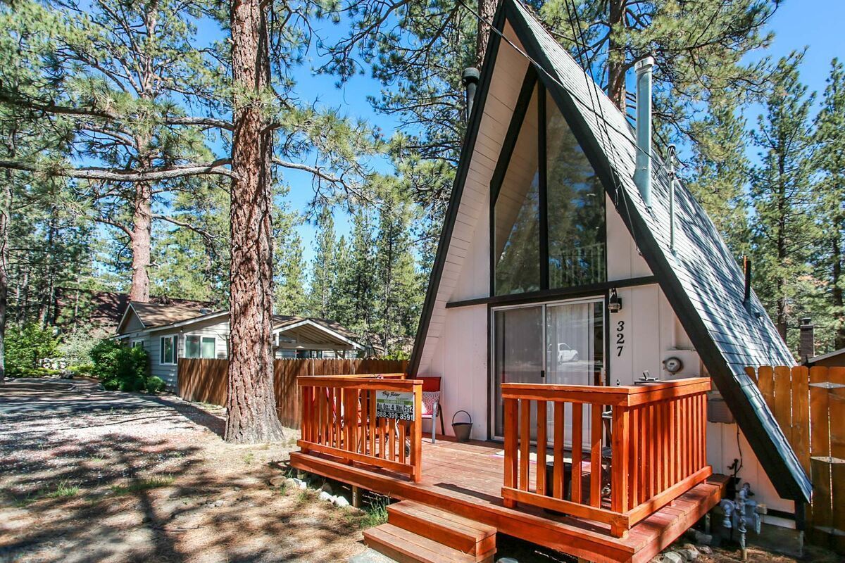A small a-frame house with huge windows and a nice porch.