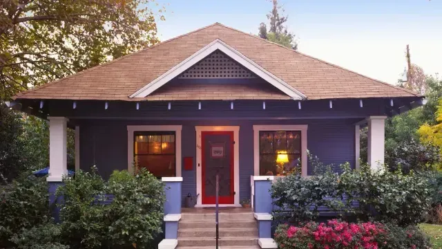 A blue house with a brown roof and a red door