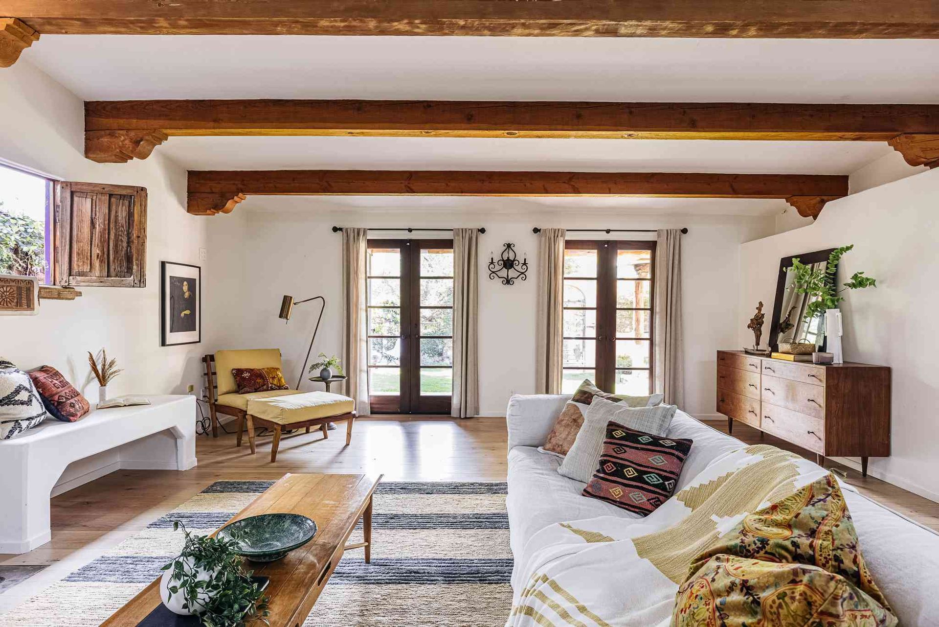A living room with a white couch and wooden beams.