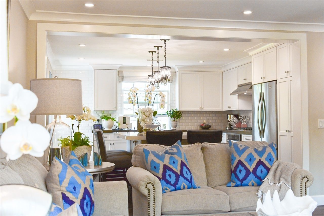 A living room with a couch and pillows and a kitchen in the background