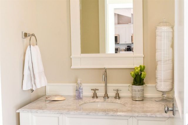 A bathroom with a sink , mirror and towel rack.