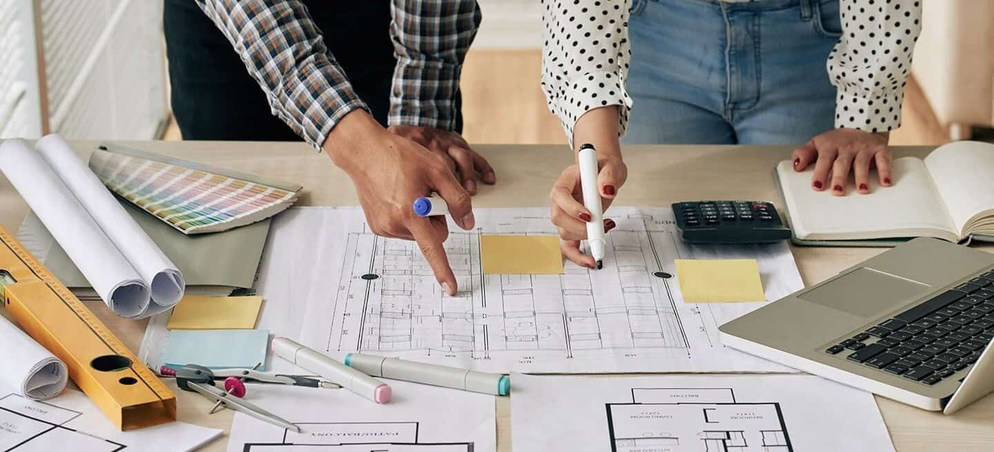 A man and a woman are looking at a blueprint of a house.