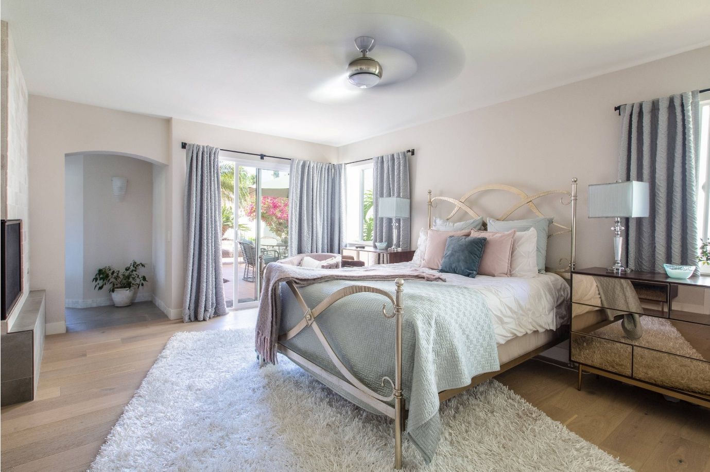 A bedroom with a bed , dresser , nightstand and ceiling fan.